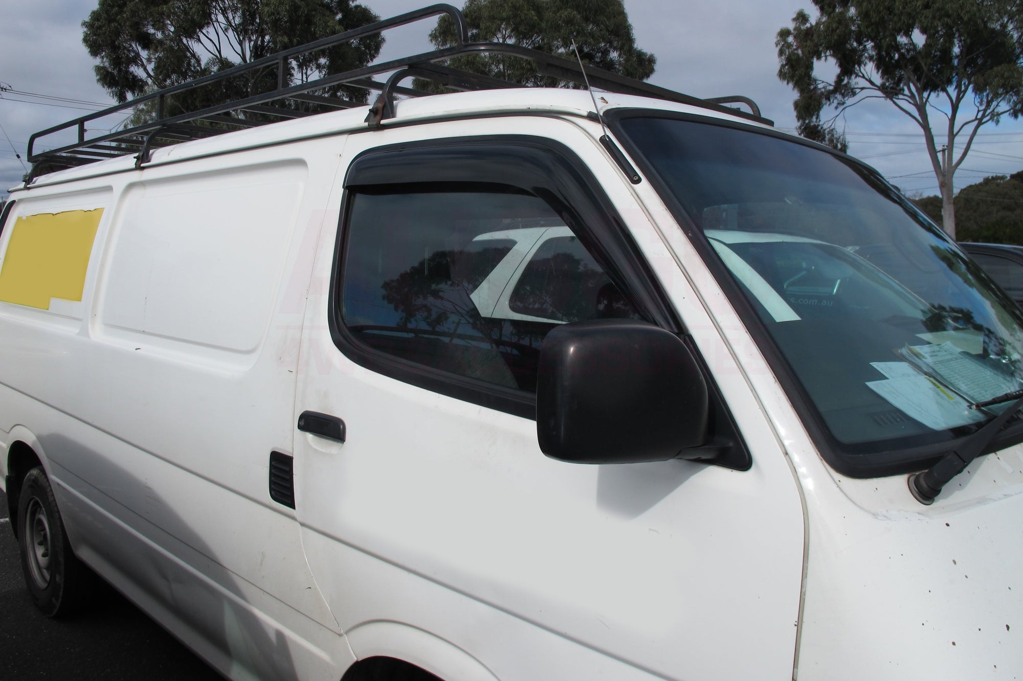 Side view of a white Toyota HiAce parked in an outdoor carpark.