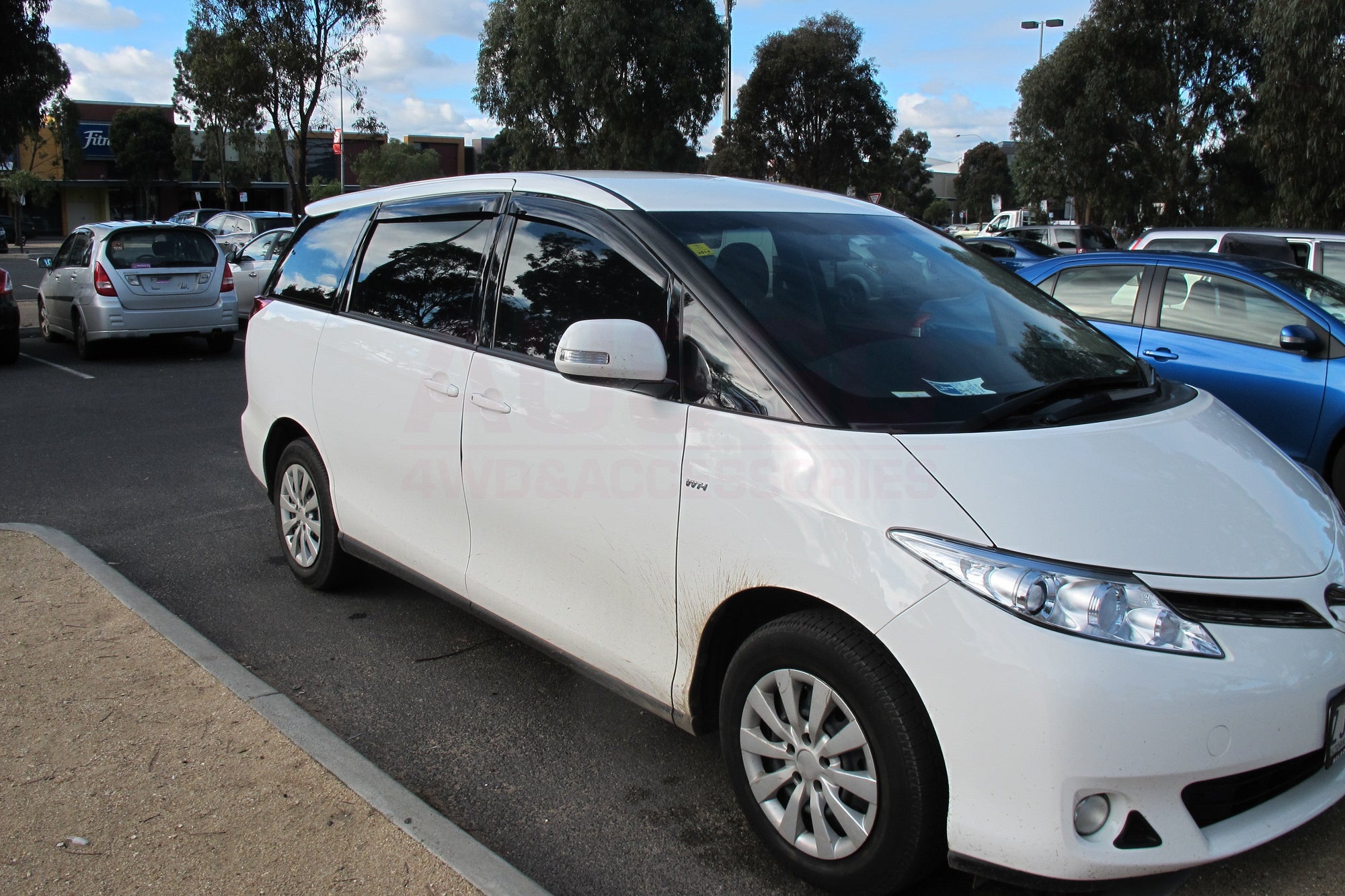 Side view of a white Toyota Tarago parked in an outdoor carpark.