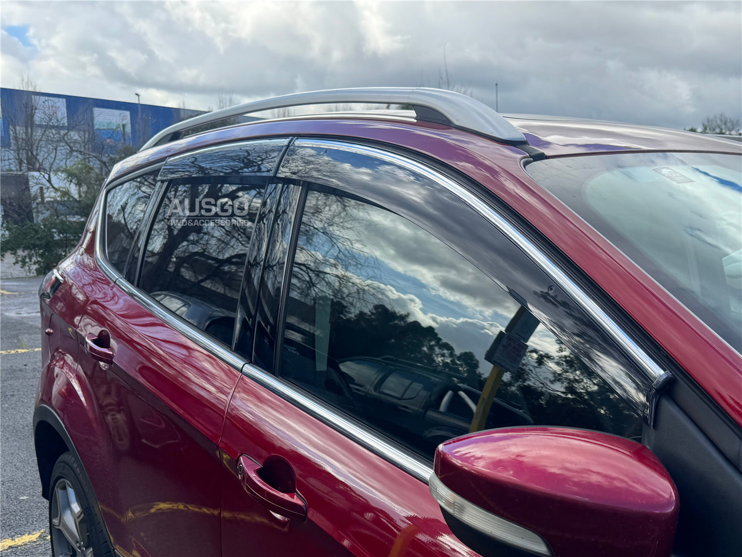 A side view of a red Toyota C-HR parked in an outdoor carpark.