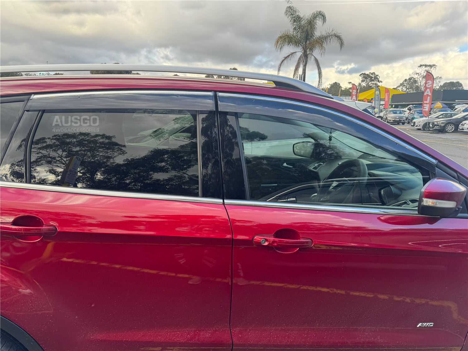 Side view of a red Ford Kuga with weather shields attached to a window.