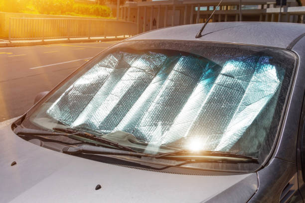 Car parked in sunlight with a reflective sunshade on the windshield to block UV rays and reduce interior heat buildup.
