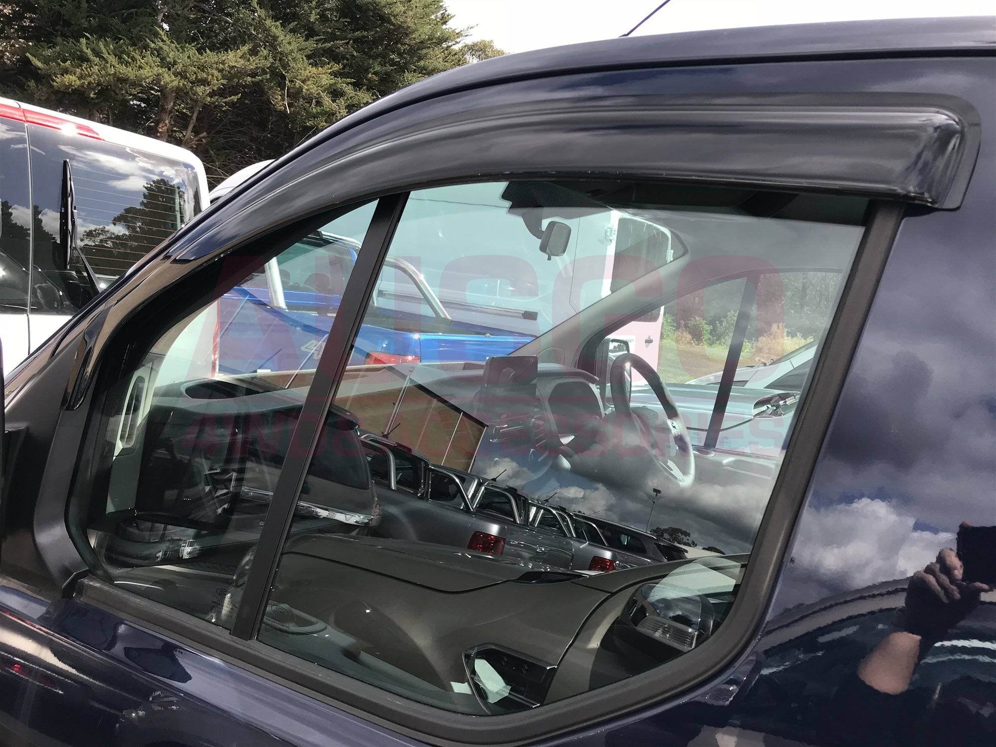 Side view of a black Ford Transit with a weather shield attached to the passenger side window. 