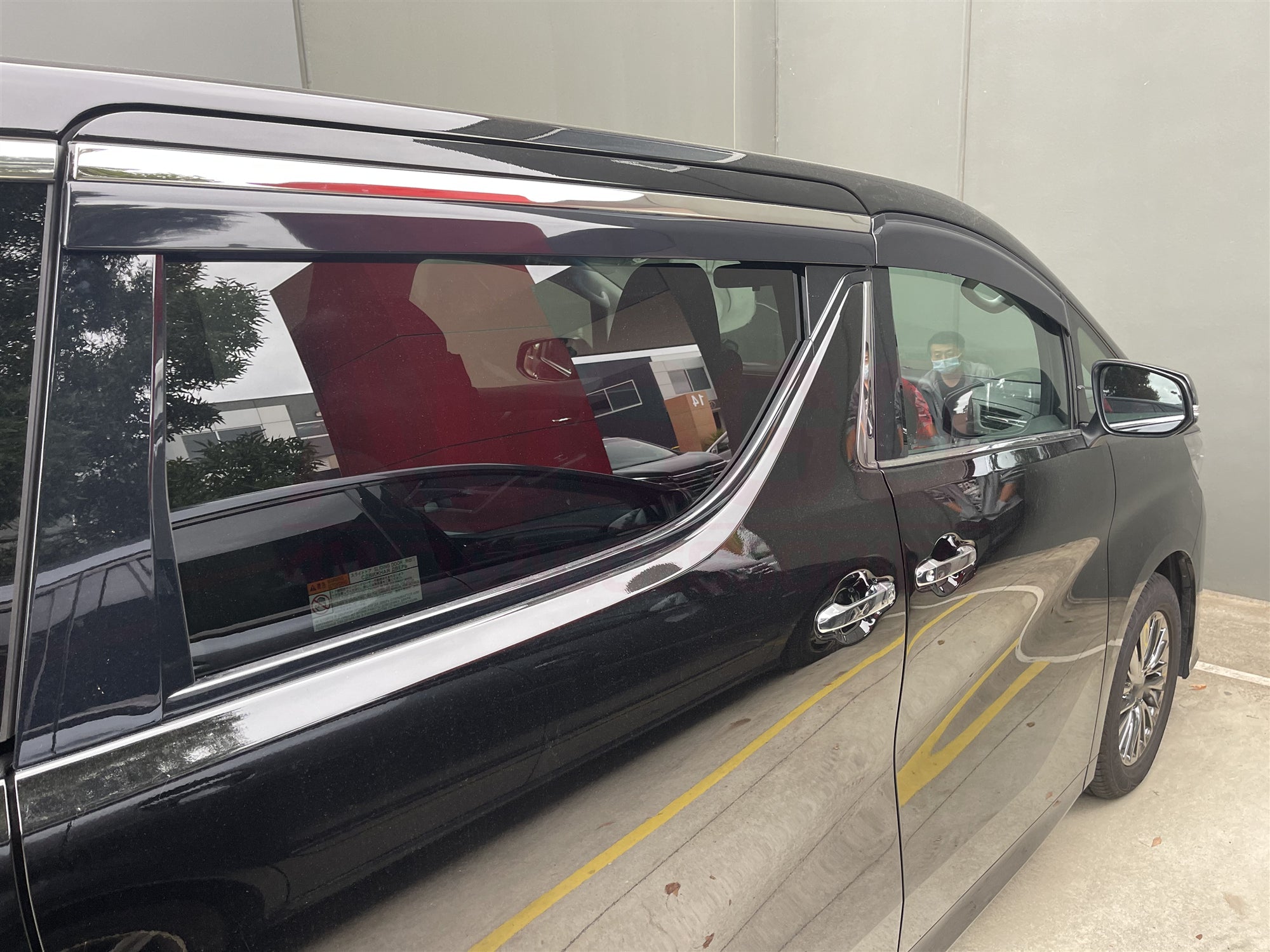 A black Toyota Vellfire parked in an indoor carpark.