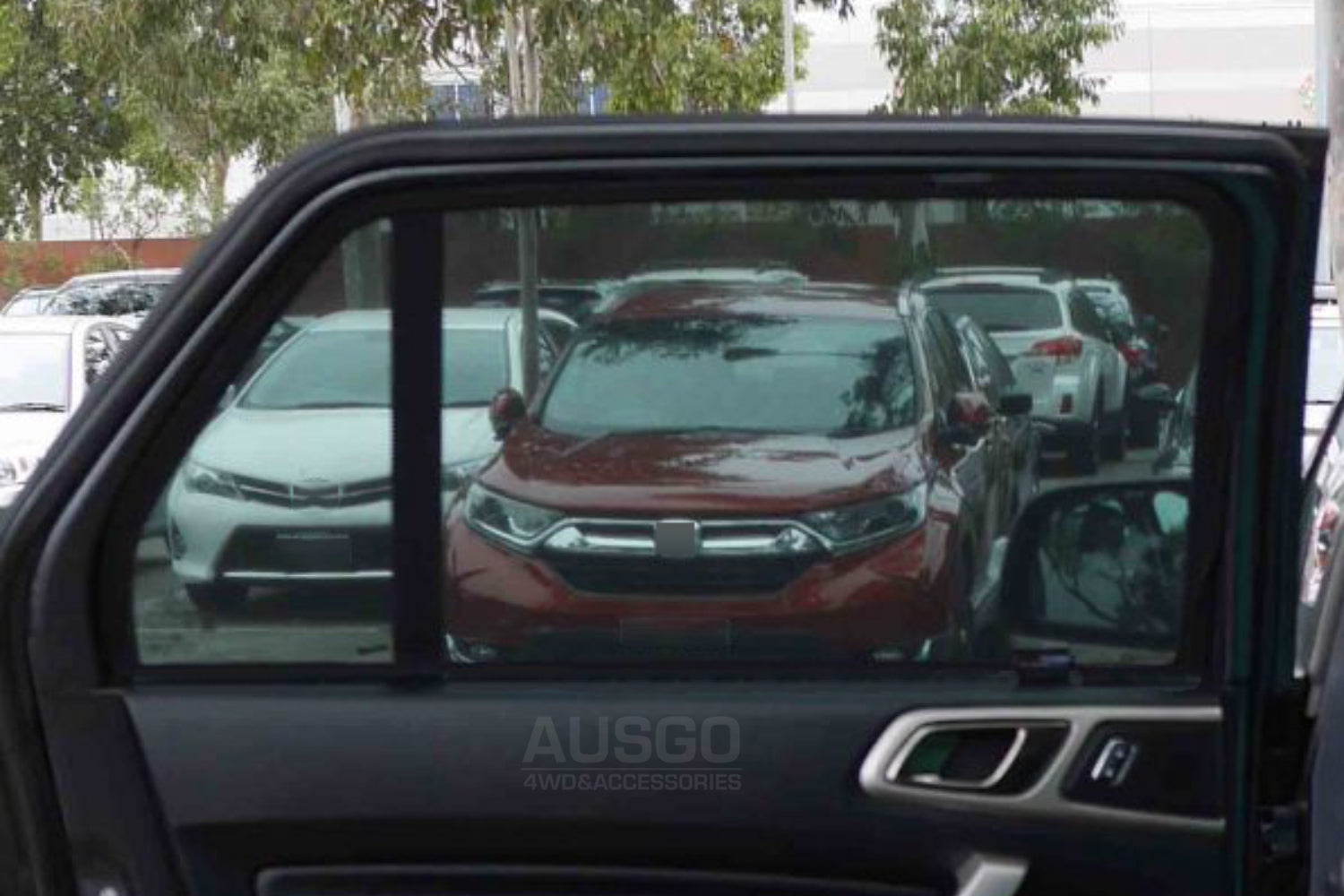Car interior view through an open door shows other parked cars in a lot.