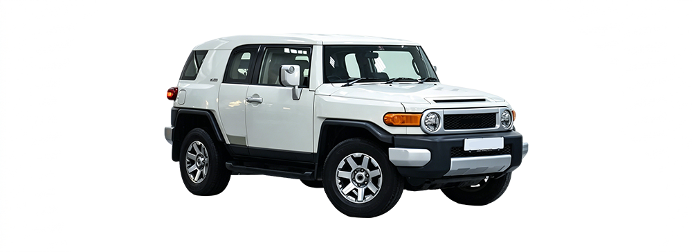 Red Toyota FJ Cruiser parked on grassy terrain near trees. 