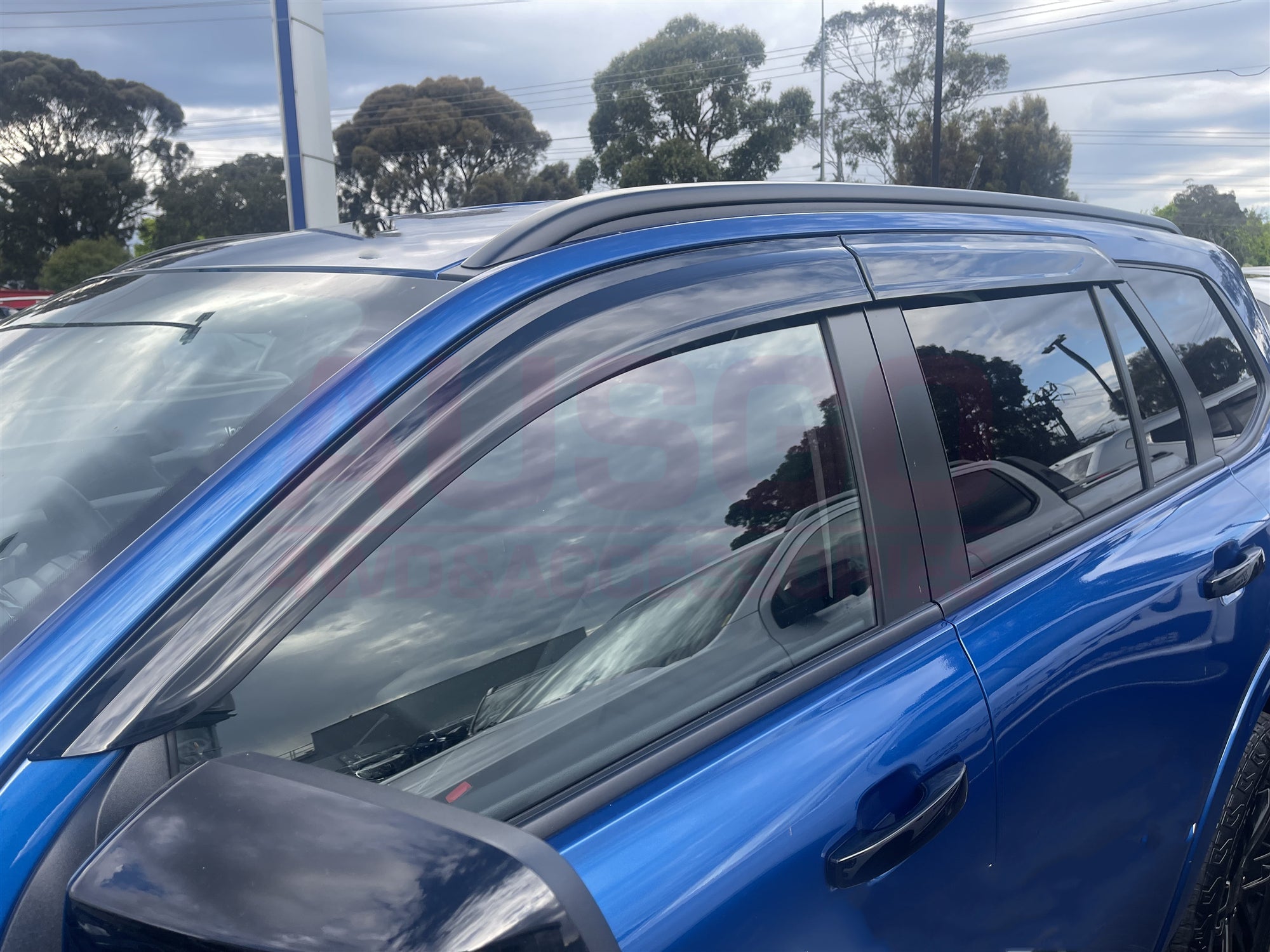 Side view of a blue Ford Everest with weather shields attached to the windows.