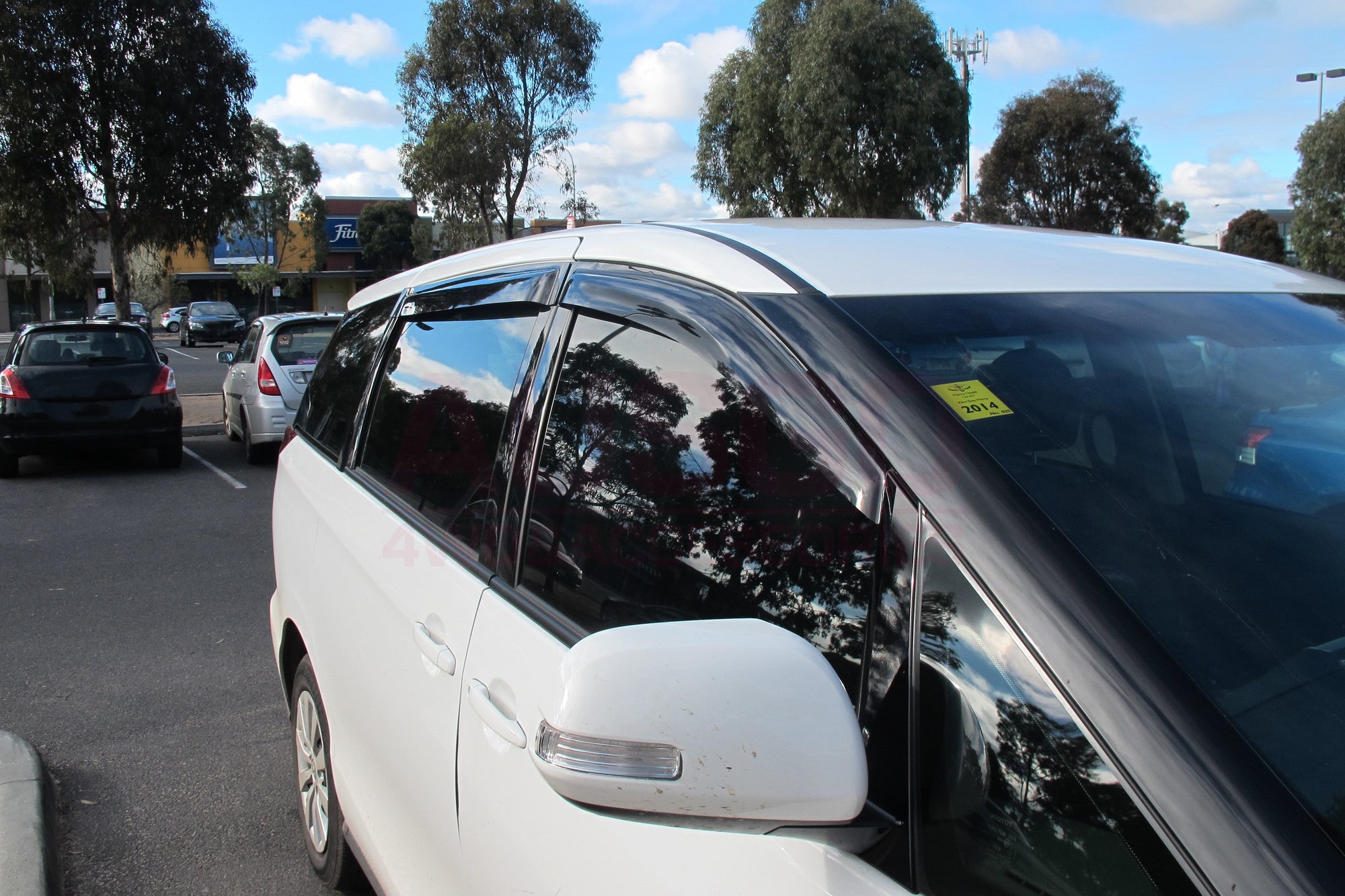 Side view of a white Toyota Tarago with black weather shields parked in an outdoor car park.