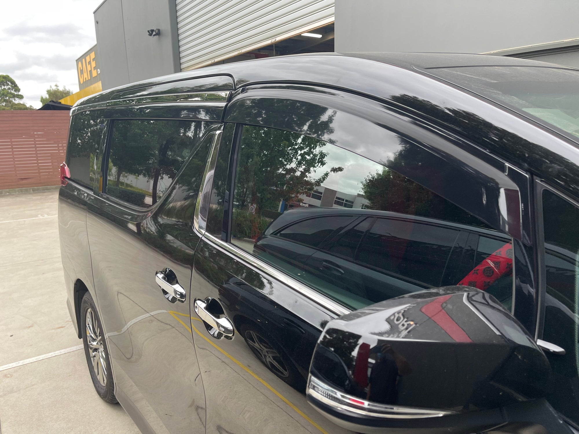 Side view of a black van with weather shields attached to the windows.