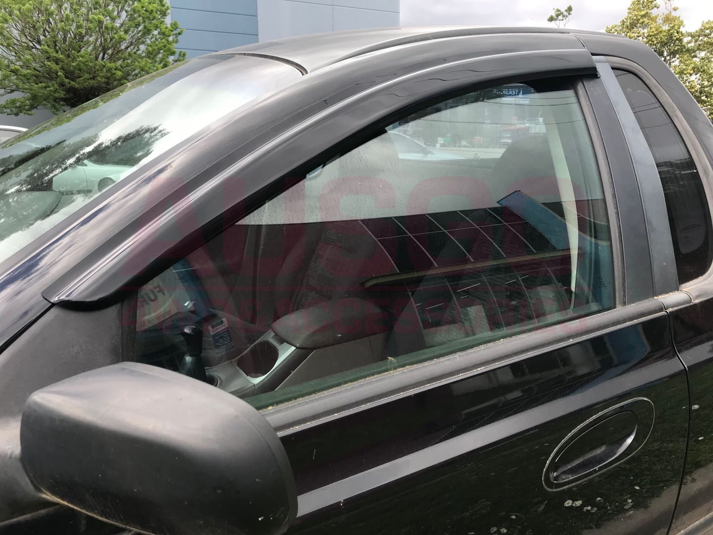 Side view of a black Ford Fairlane with weather shields attached to the window.