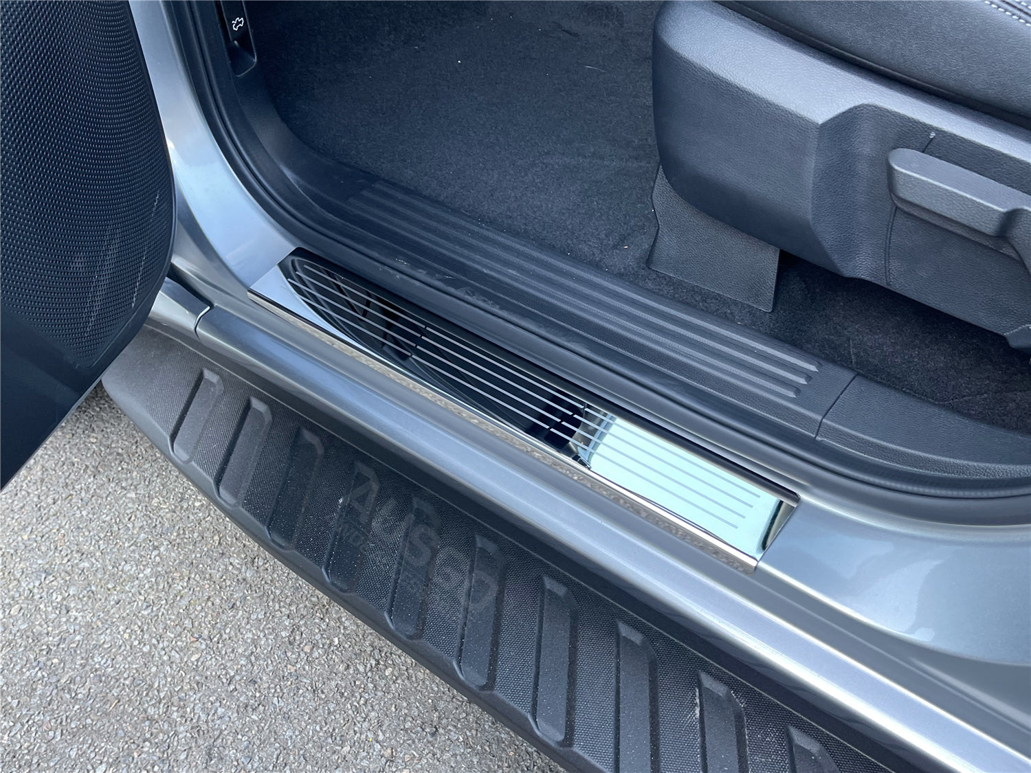 A zoomed in photo of AUSGO door sill protector installed in a car.