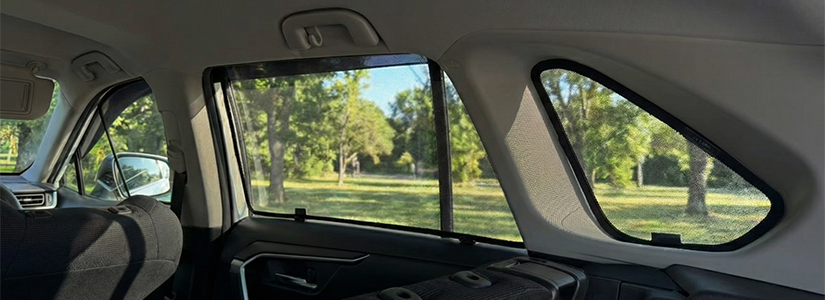 A sun shade attached to the passenger seat window of a car.