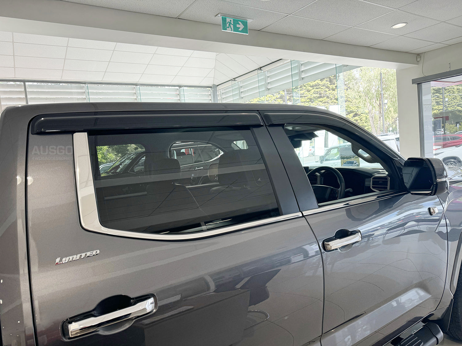 Side view of a dark grey Toyota Tundra with black weather shields attached to the windows.